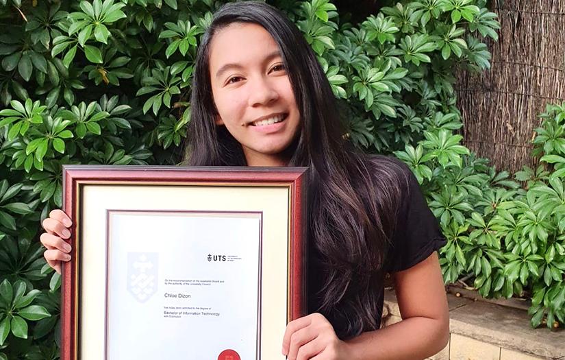 Young woman holding a graduation certificate while smiling and looking at the camera