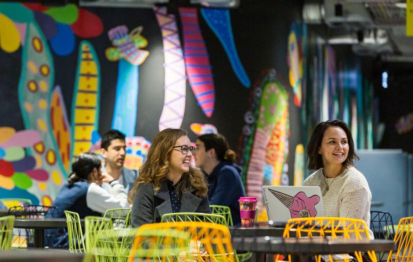 Two young women having a coffee at a table in food court