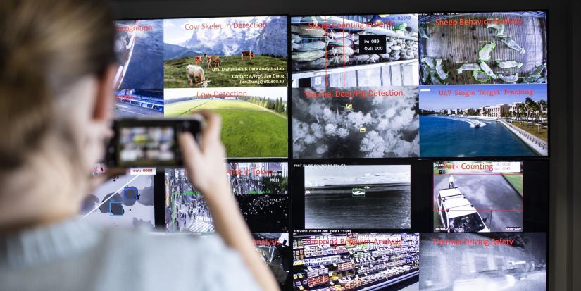 Person in foreground taking a photo of a multimedia data screen