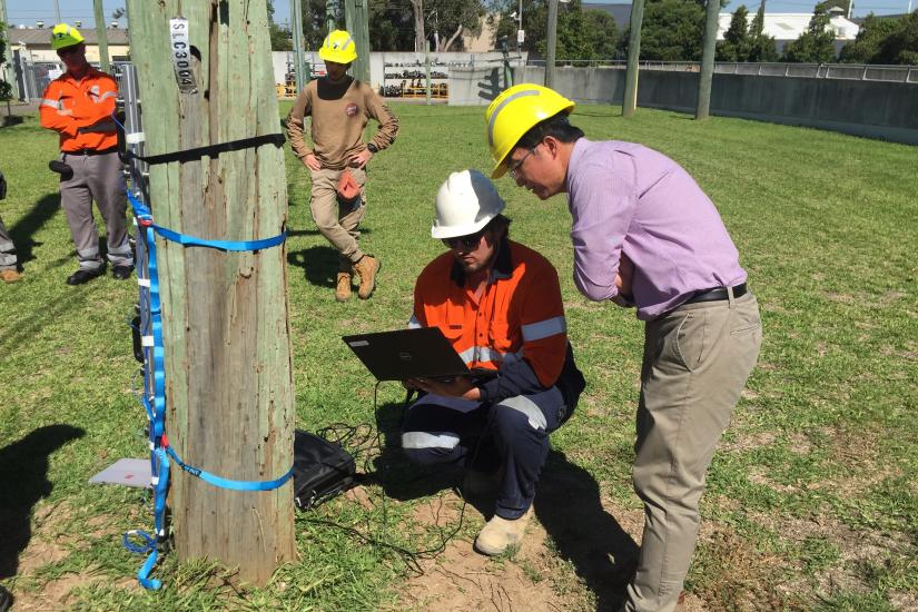 Man outdoors in hard hat using a laptop