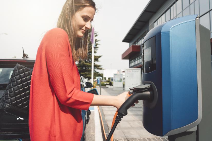 Woman charging electric vehicle