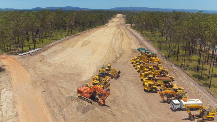 Maintenance vehicles on dirt road surrounded by bush