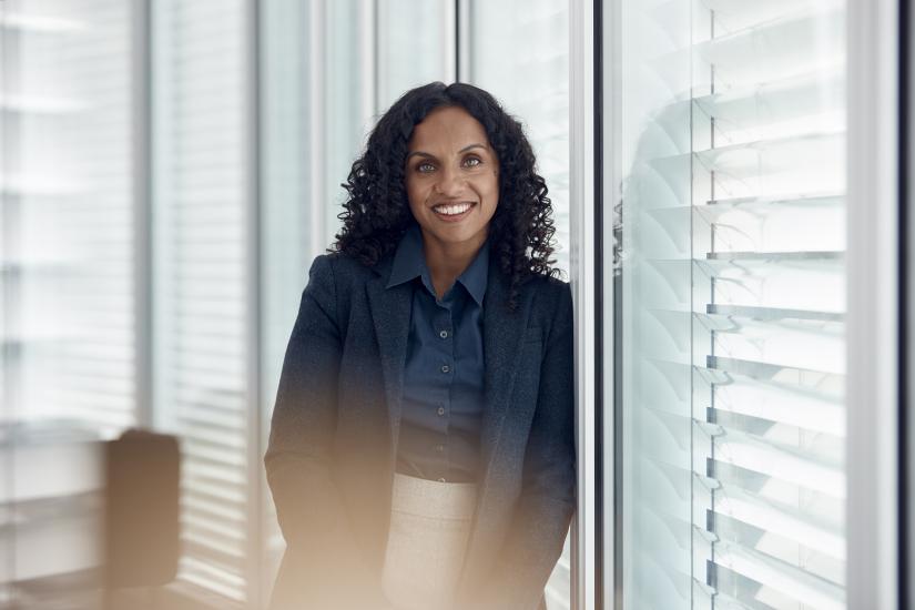 A woman stands in an office smiling at the camera