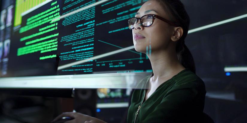 A young woman looking at see through data while seated in a dark office