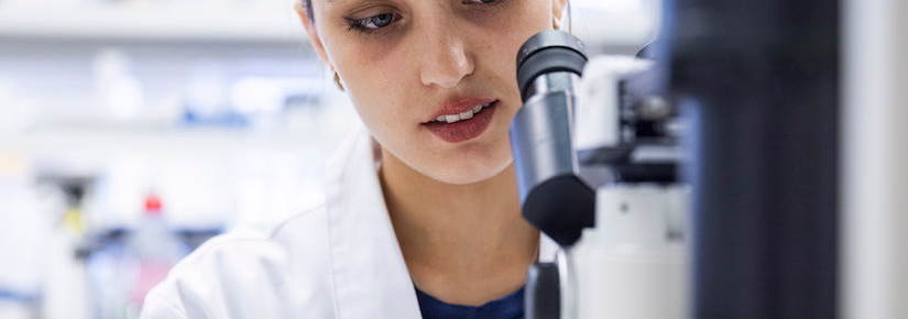 Raissa Gill looking through a microscope