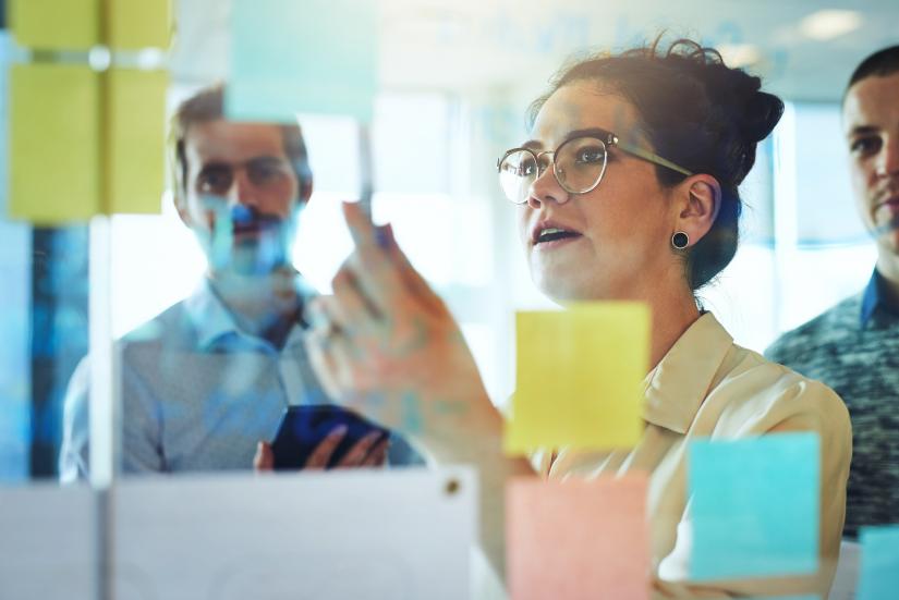 People standing behind a glass wall with sticky notes