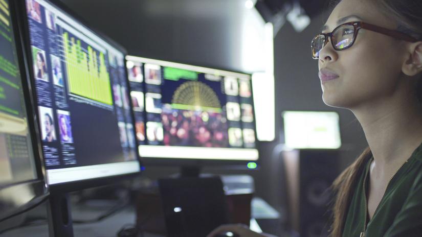 A woman looking at data models on a computer screen