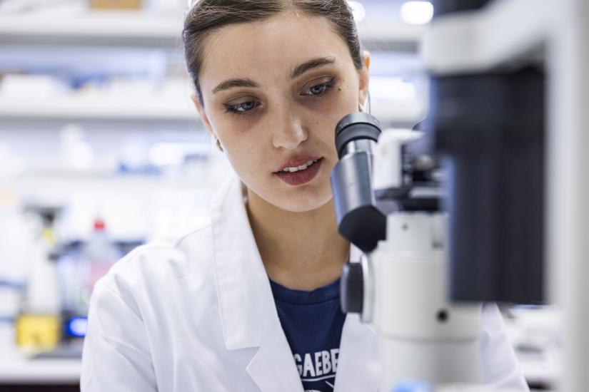 Raissa Gill looking through a microscope