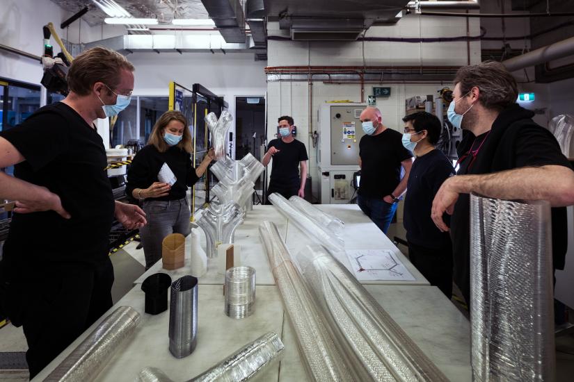 project UTS and BVN team members stand around table with multiple 3D printed components on it