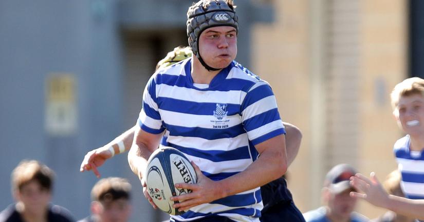 Taine Woodford carrying the ball and looking to pass during a rugby league game