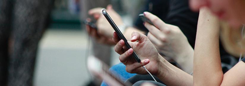 row of people holding smartphones