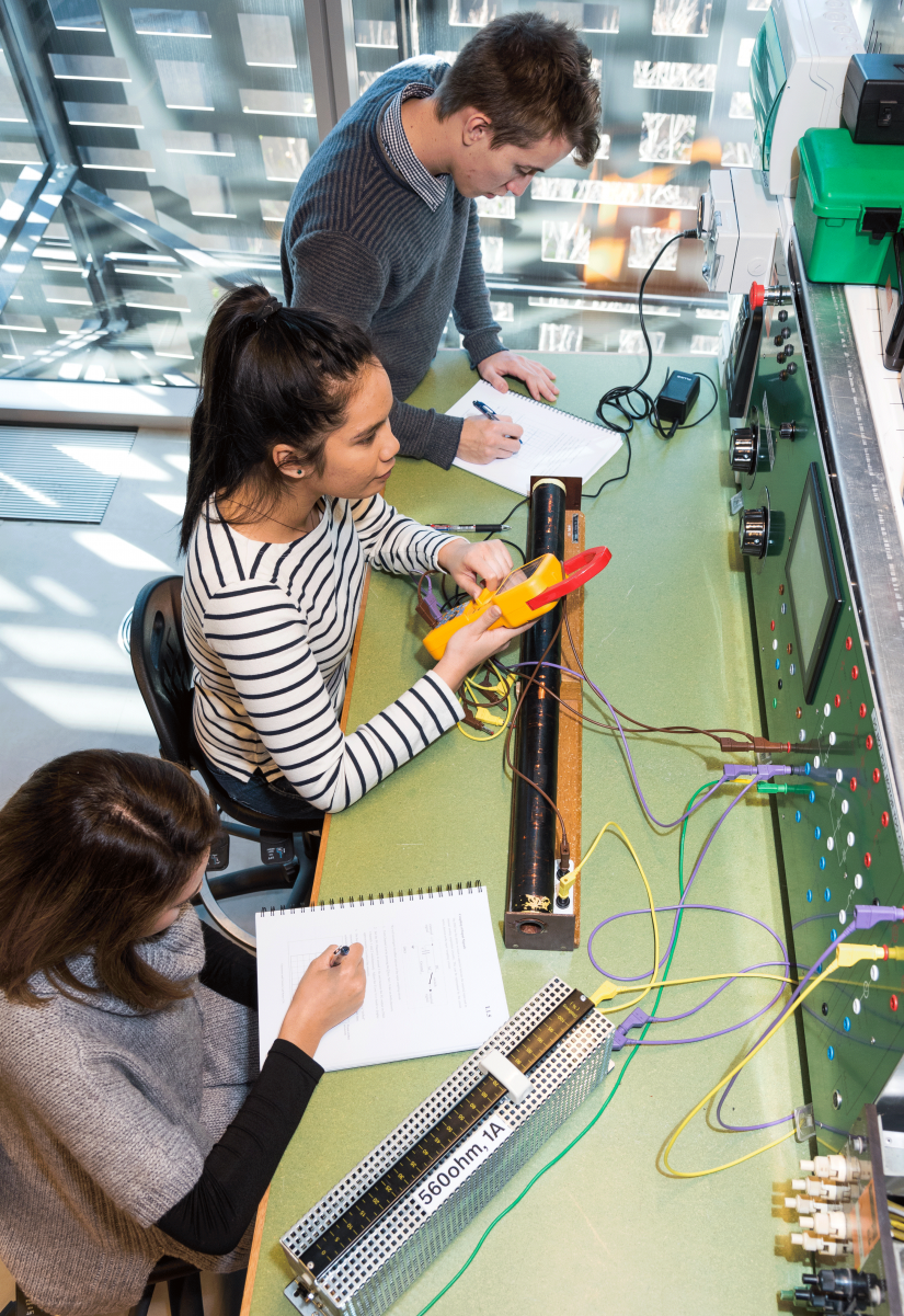Overhead view of three students working on their electronics project