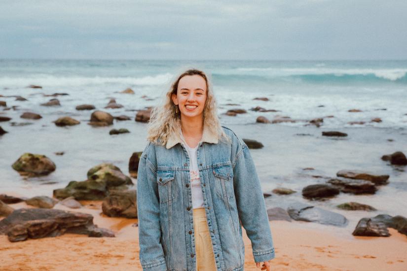 Girl at the sea shore, smiling at the camera