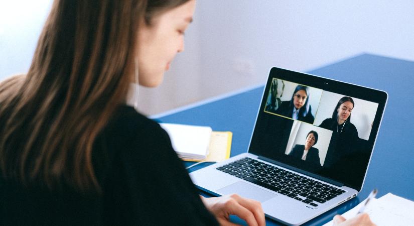 A women at her desk meeting with three other women on her laptop via Zoom.