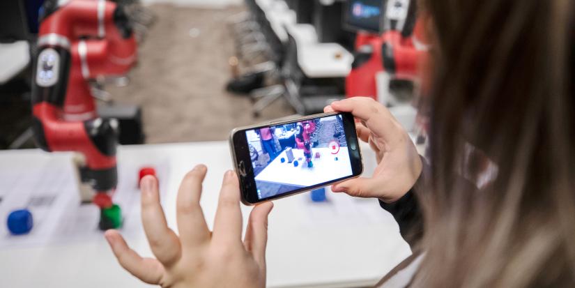 A Galuwa student films the robot in action after she's helped to program it to move