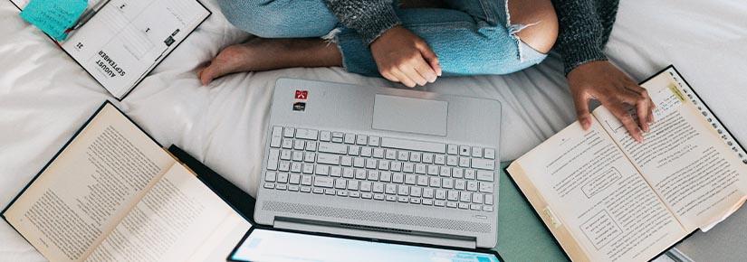 laptop and books placed on bed