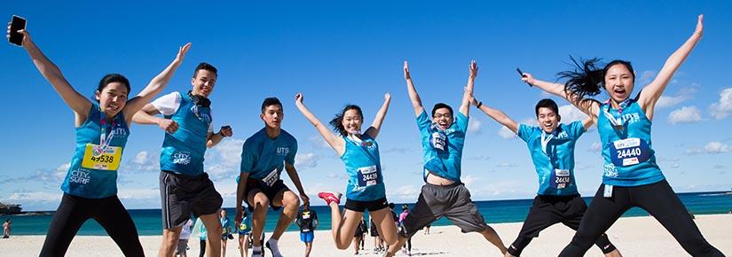 Group of students doing star jumps on the beach