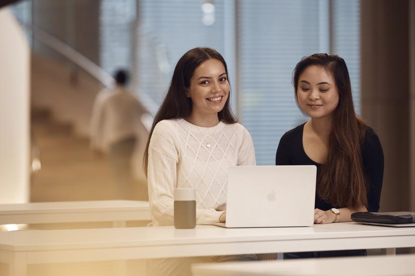 Two students sharing laptop on campus