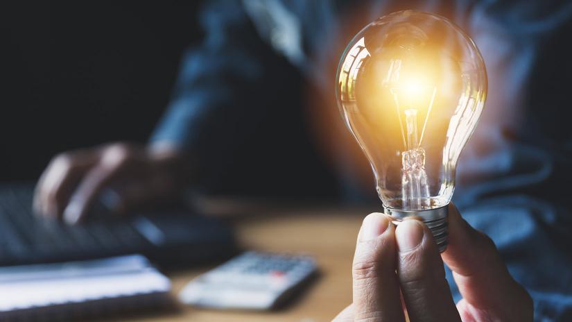 Glowing lightbulb held in man's hand