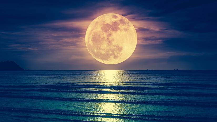 Full moon rising over ocean