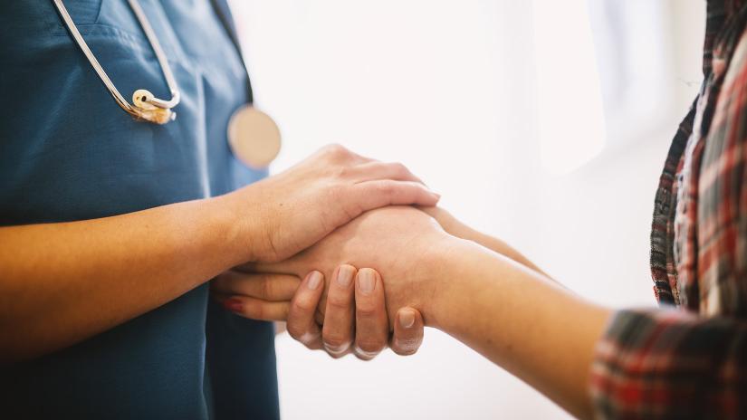 Health nurse holding patients hand