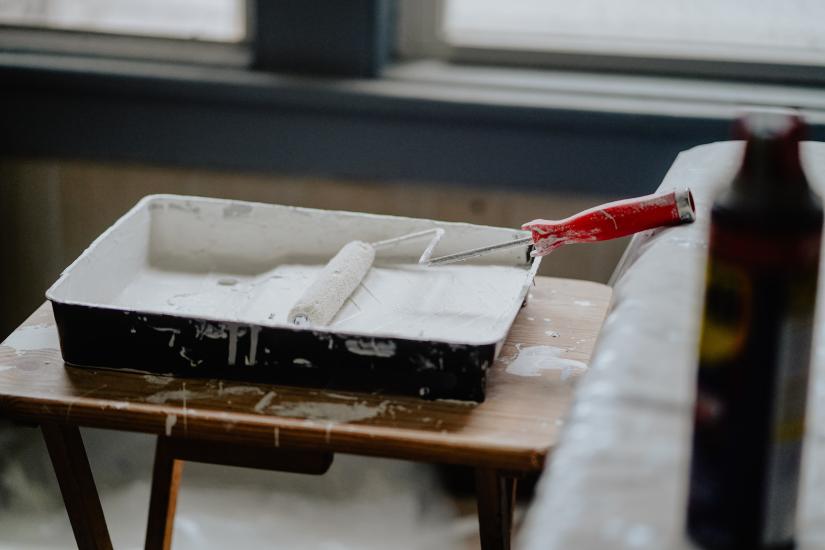 Paint roller in white paint and tray, renovating a room