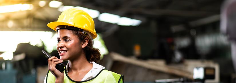 Woman in hard hat and high vis on walkie talkie site