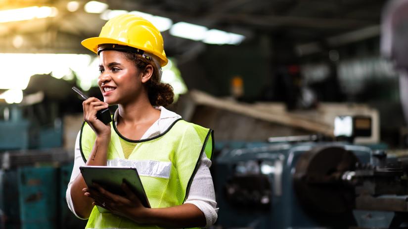 Woman in hard hat and high vis on walkie talkie site