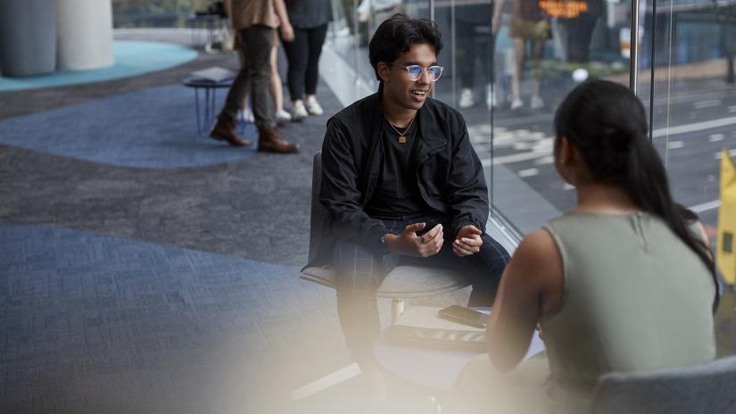 Student wearing black jacket interacting on UTS campu