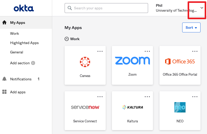 Screenshot of the Okta dashboard with a left nav menu, tiles with app icons and text, and a red box in the top-right corner highlighting a drop-down arrow