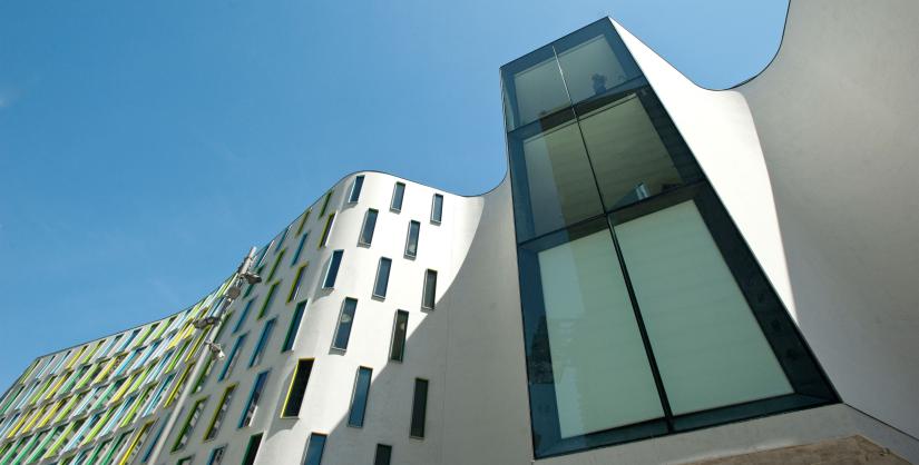Curved white building with small rectangular windows and close up of a large rectangular window