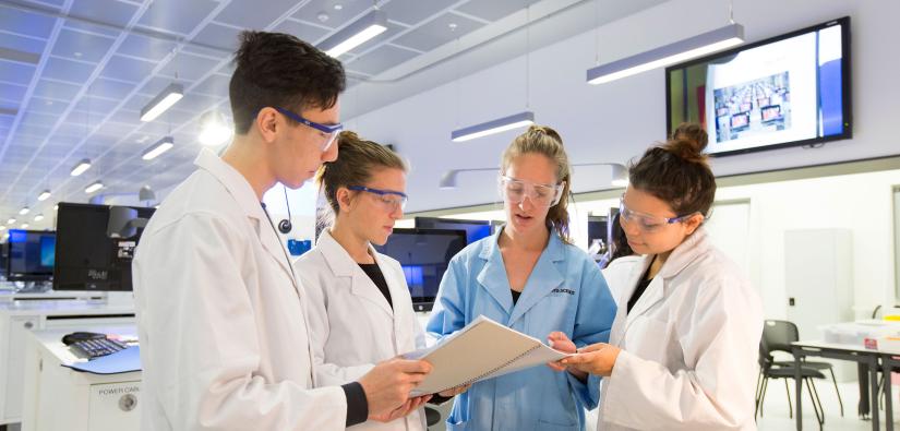 Lab teacher looking at document with three students