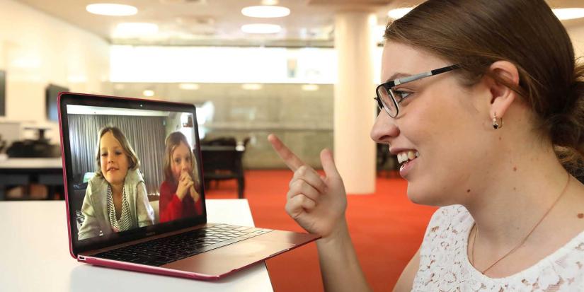 Speech pathologist gesturing whilst talking with two children on facetime