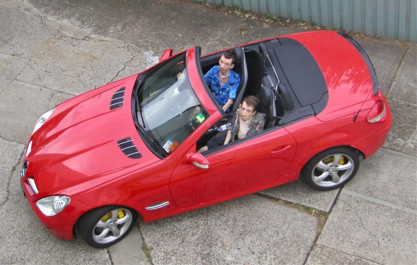 Two men sitting in a red convertible