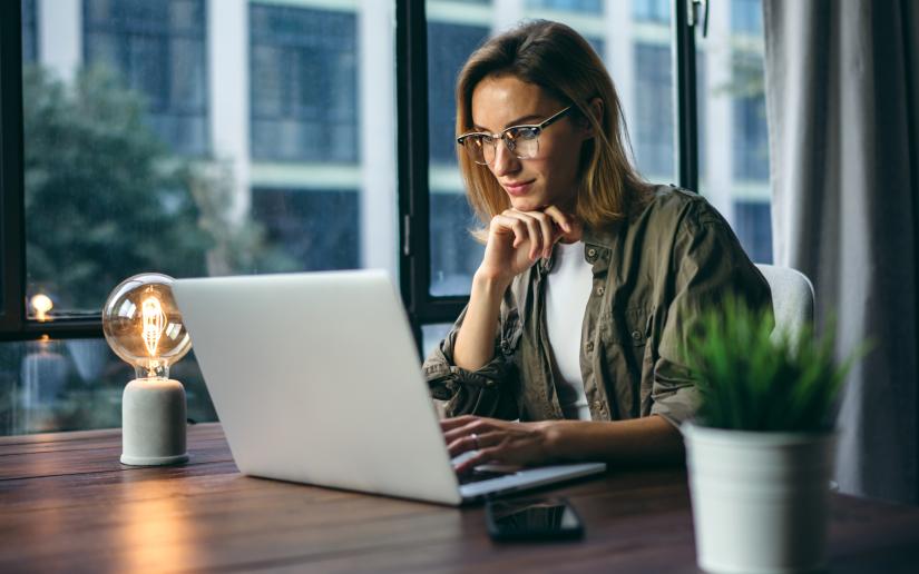 A woman sit pensively at a computer.