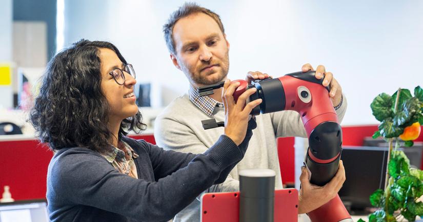 Robotics researchers in the lab manipulating an autonomous robot