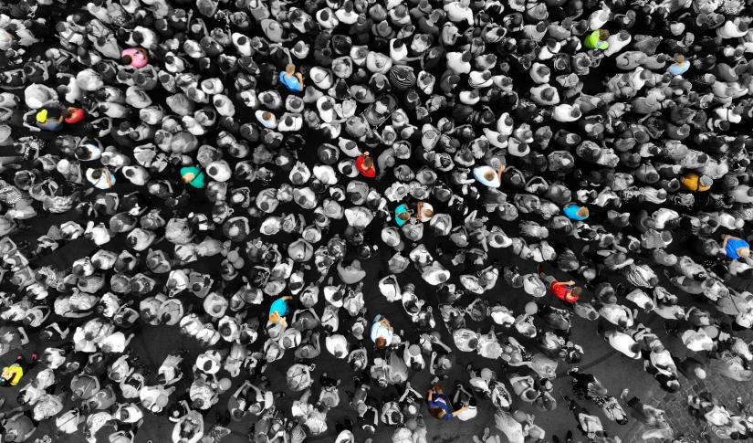 Special people amid the crowd concept with colorful persons amid the monochrome people. Top view from drone.