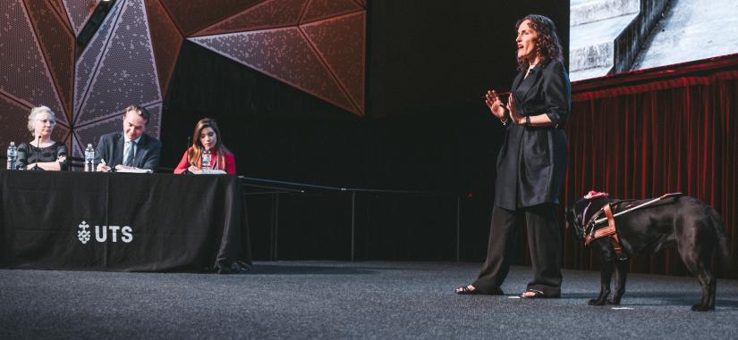 Megan Taylor with guide dog and 3MT judging panel