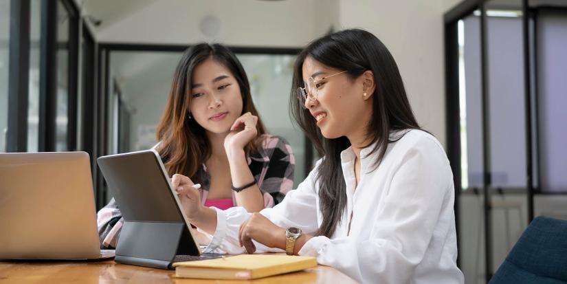 Two women looking at tablet at a desk