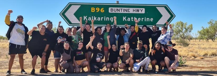 Group of students sanding on the road in front of a road sign