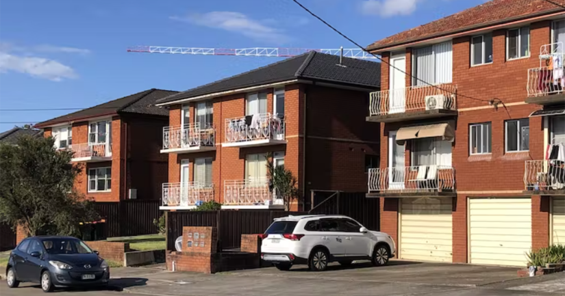 View of 1960s apartment block with two cars on the street in front