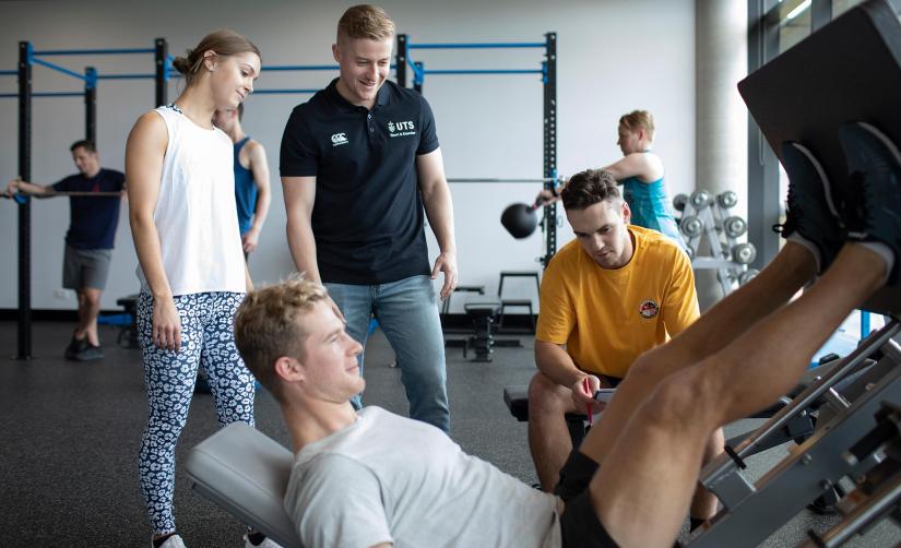 students watch as man does leg press in gym
