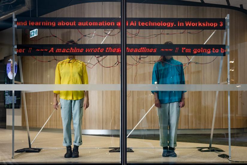 Two people stand with their faces obscured by a screen. 