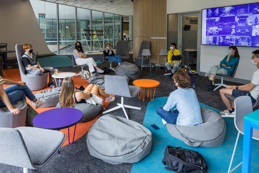 A room with people sitting on charis and bean bags talking. 