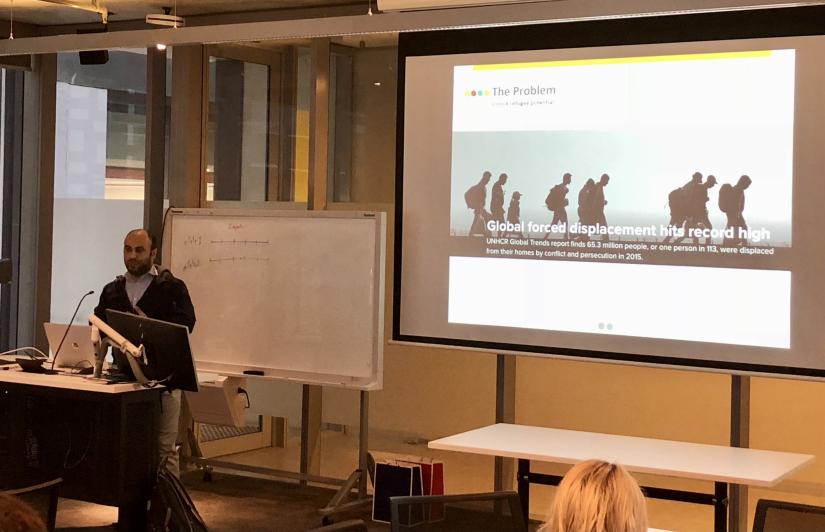 guest speaker standing in front of slide with text about refugee migration