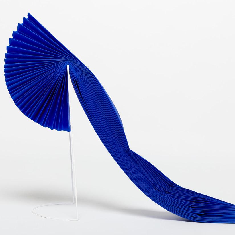 A pleated piece of blue fabric draped over a white support