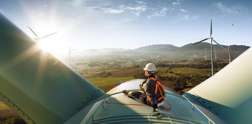 Energy worker sitting on top of a solar wind turbine