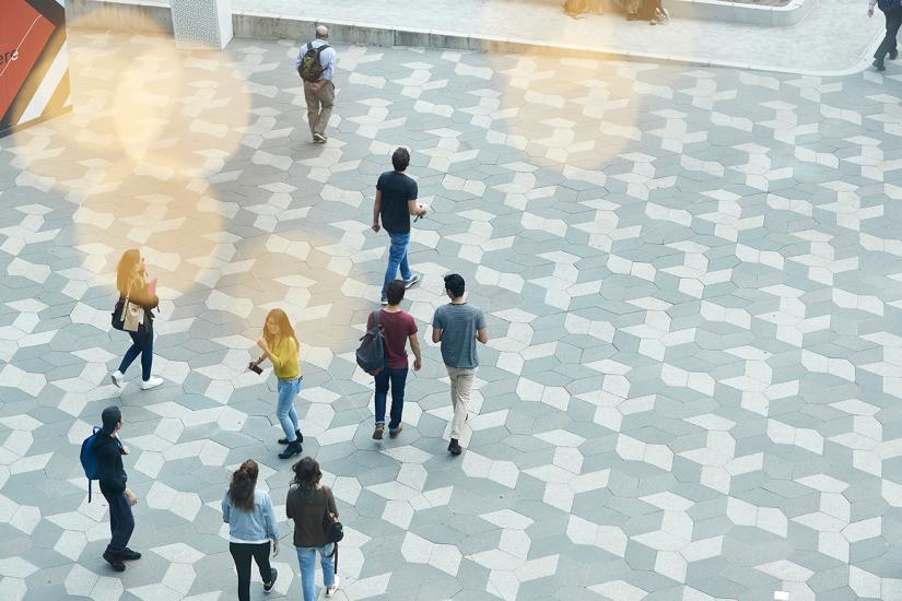 Aerial photo of students walking across a tiled outdoor flooring area