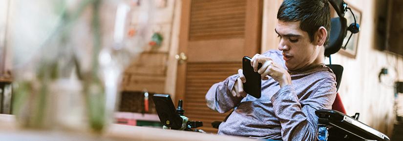 Stock picture of a young man with physical disabilities using mobile technology