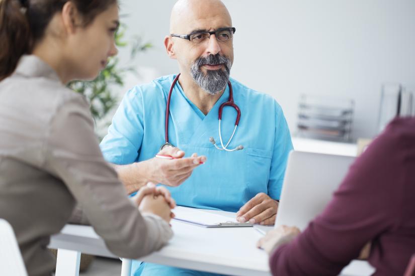 Medical professional in scrubs talking to two people